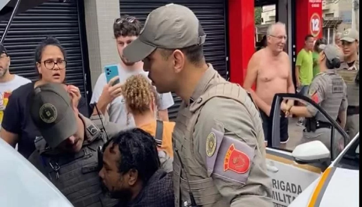 Homem negro vítima de facada é detido pela BM em Porto Alegre, enquanto o suposto agressor conversa com policiais | Foto: Renato Levin Borges