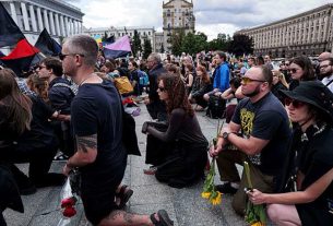 Pessoas de joelhos durante a cerimónia de despedida de David Chichkan, um militar e artista ucraniano, na Praça da Independência em Kiev, Ucrânia, na segunda-feira, 18 de agosto de 2025